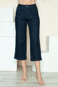 Person wearing dark blue jeans standing in a minimalistic room.