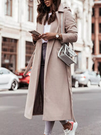 Person wearing a long beige coat on a city street