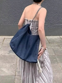 Person holding a blue bag with a gray background