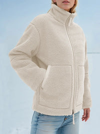 Person wearing a beige fleece jacket against a light blue background