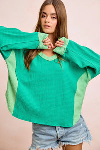 Woman wearing a green sweater with color-block design on a beige background