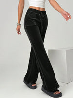 Black velvet pants worn by a person on a plain background