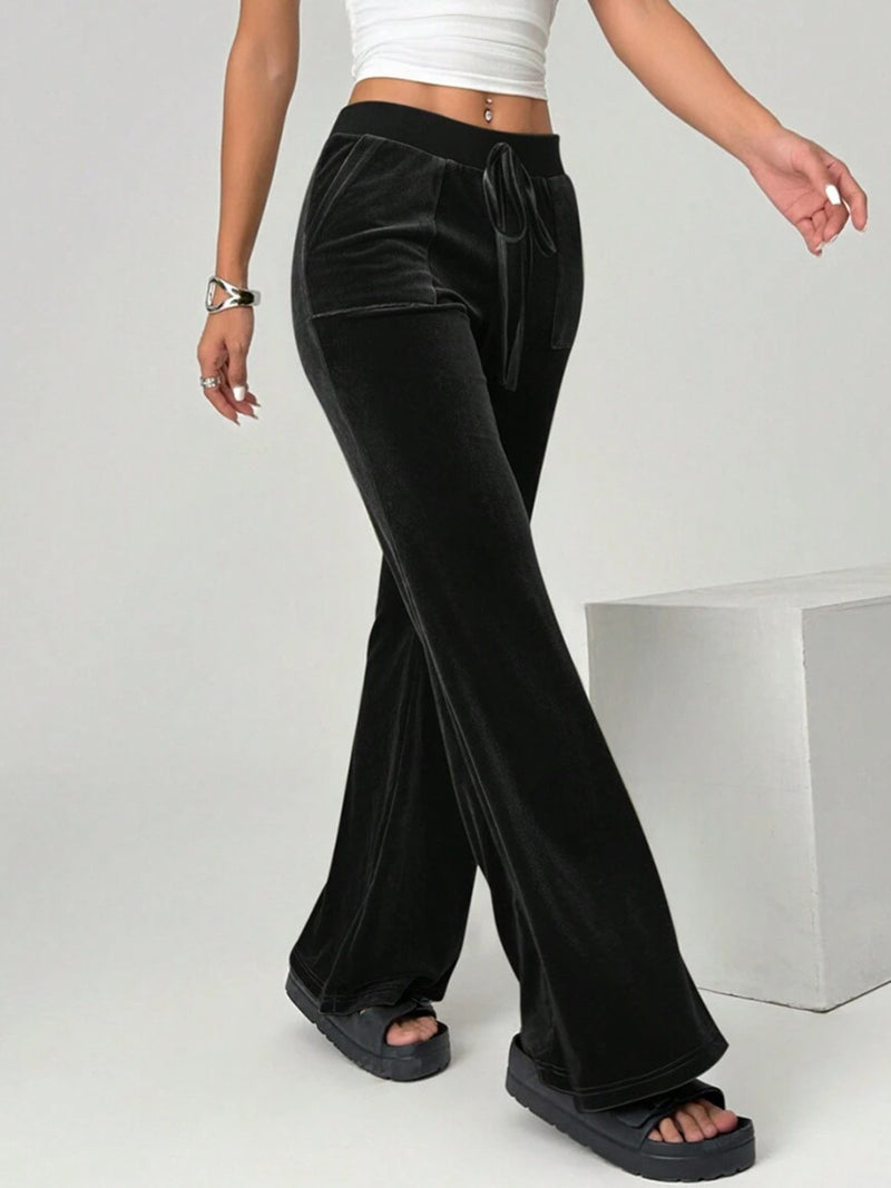 Black velvet pants worn by a person on a plain background