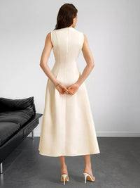 Woman wearing a white dress standing in a minimalistic room with a black couch.