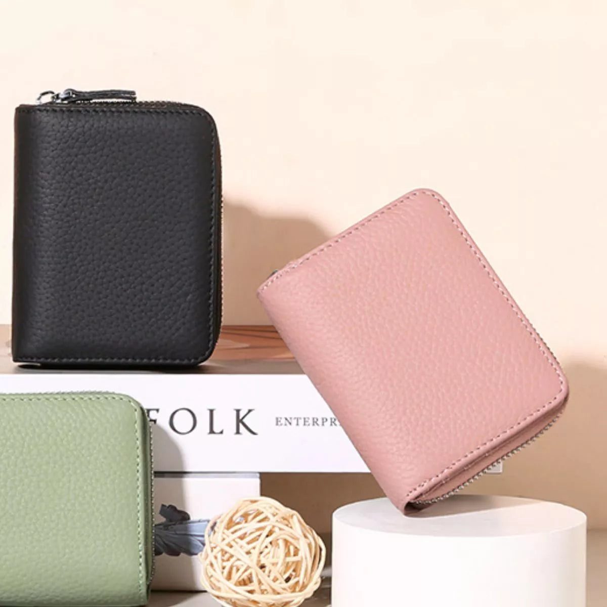 Three wallets in black, pink, and green on a light background