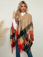 Woman wearing a plaid scarf with a neutral-toned shawl over a white shirt.