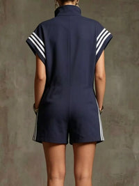 Navy blue romper with white stripes on sleeves and sides against a textured brown background