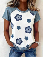 Woman wearing a white t-shirt with blue floral patterns and denim sleeves and pants.
