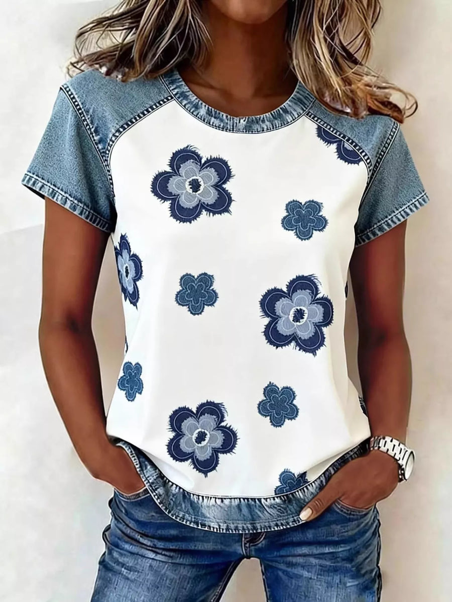 Woman wearing a white t-shirt with blue floral patterns and denim sleeves and pants.