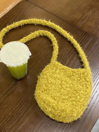 Yellow textured bag on a wooden surface with a green container next to it