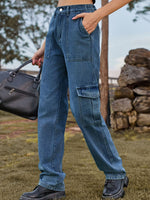 Person wearing blue jeans outdoors with a stone wall and trees in the background