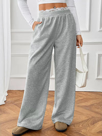 Person wearing gray sweatpants in a room with wooden flooring and white walls.