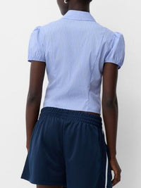 Person wearing a light blue striped shirt and navy shorts on a white background