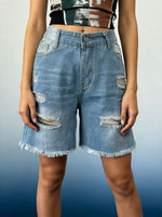 Person wearing distressed denim shorts on a gradient background