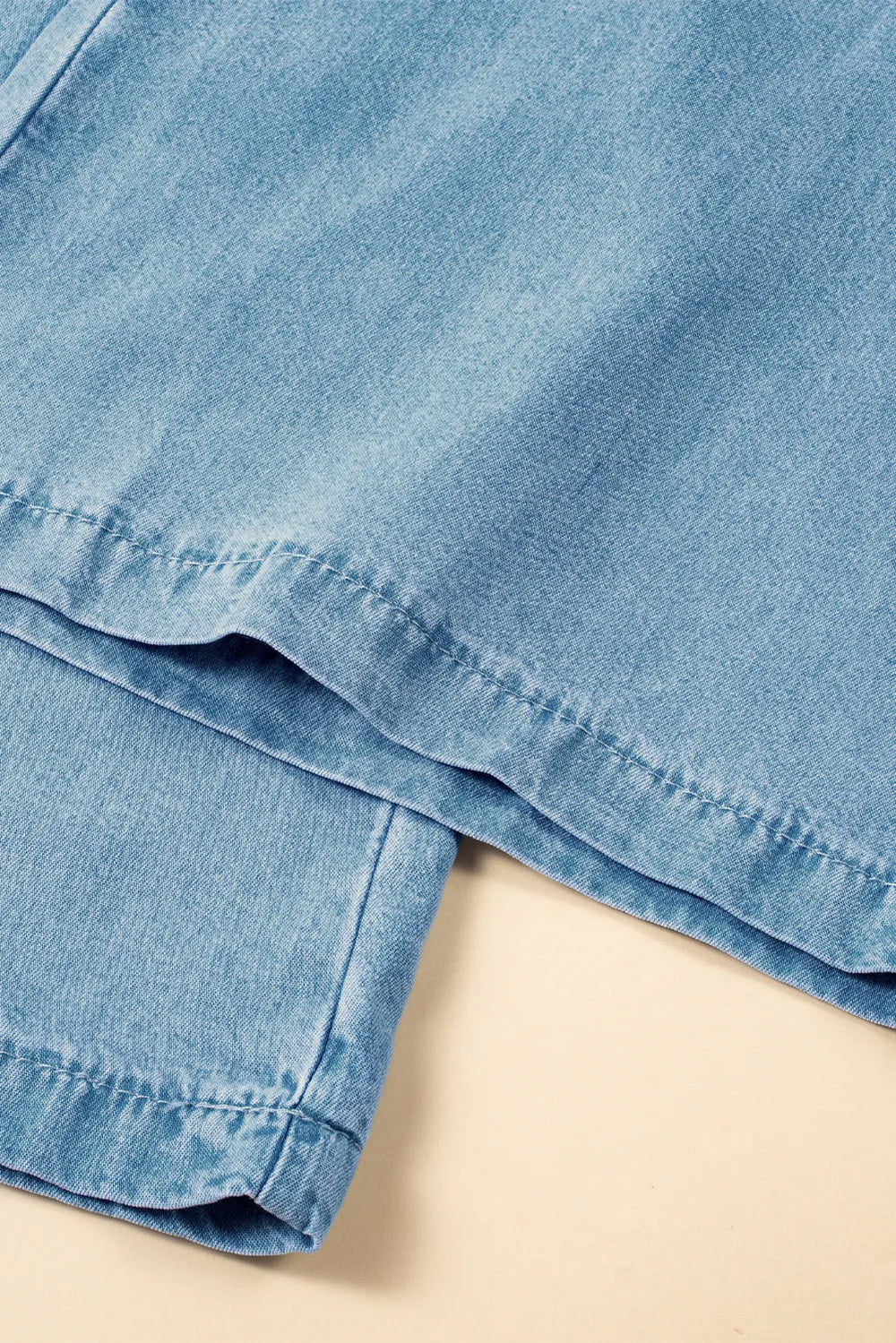 Close-up of a folded denim skirt on a beige surface