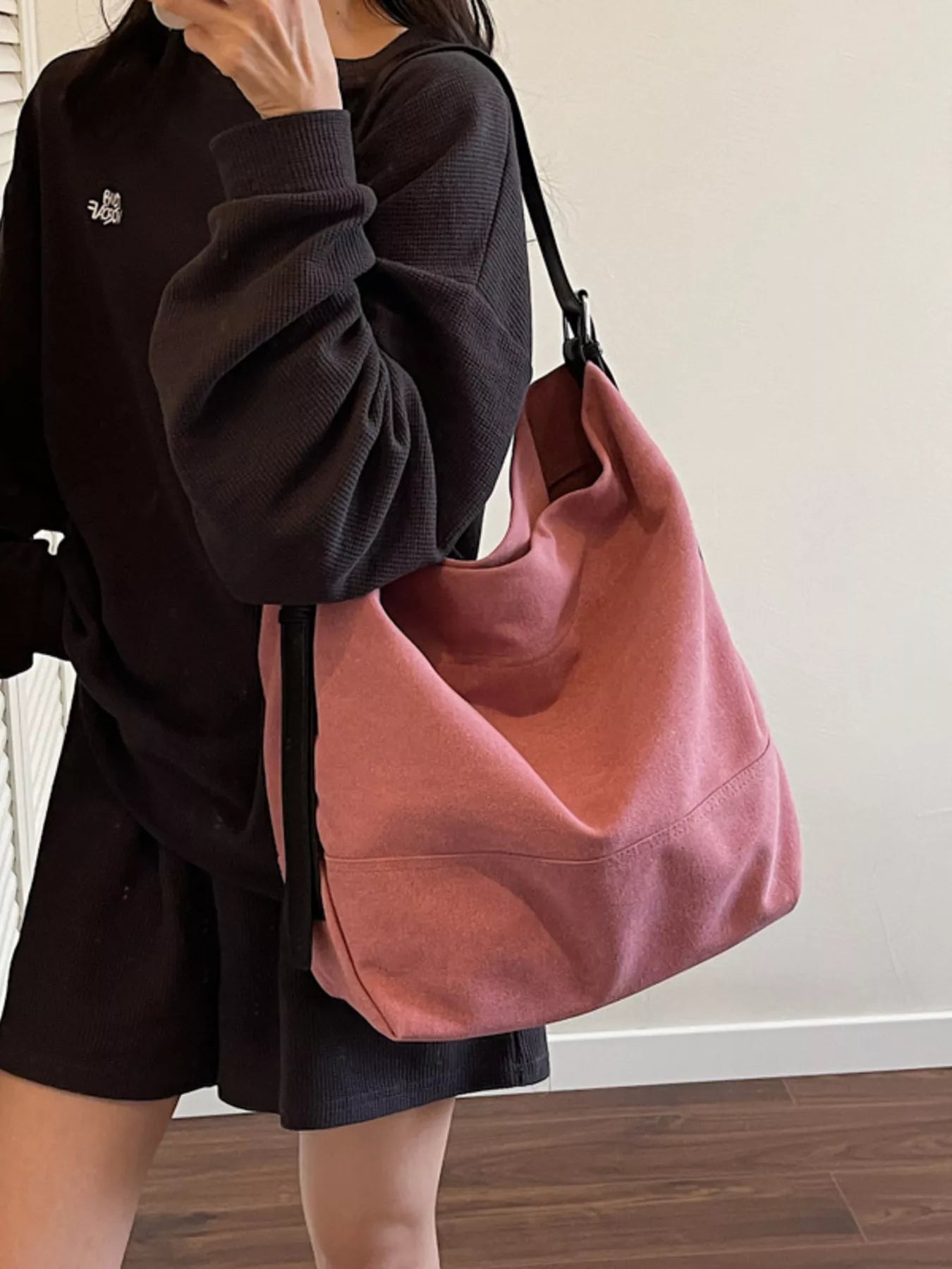 Person holding a pink handbag against a neutral background