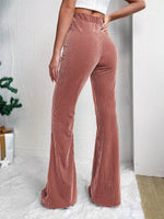 Person wearing brown corduroy flared pants against a white background