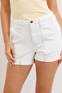 White denim shorts worn by a person on a plain background
