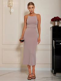 Woman in a long, light purple dress holding a glass of red wine in an elegant room.