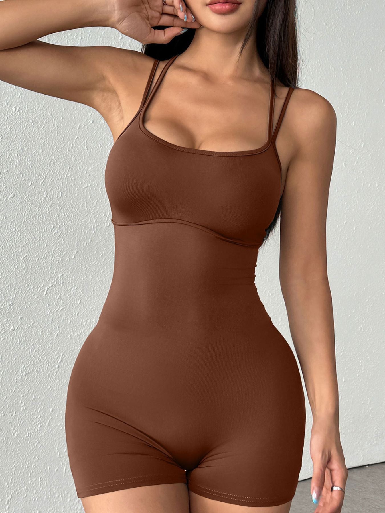 Woman wearing a brown bodysuit against a plain background