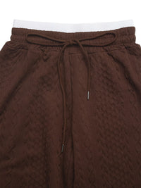 Brown textured pants with a drawstring on a white background