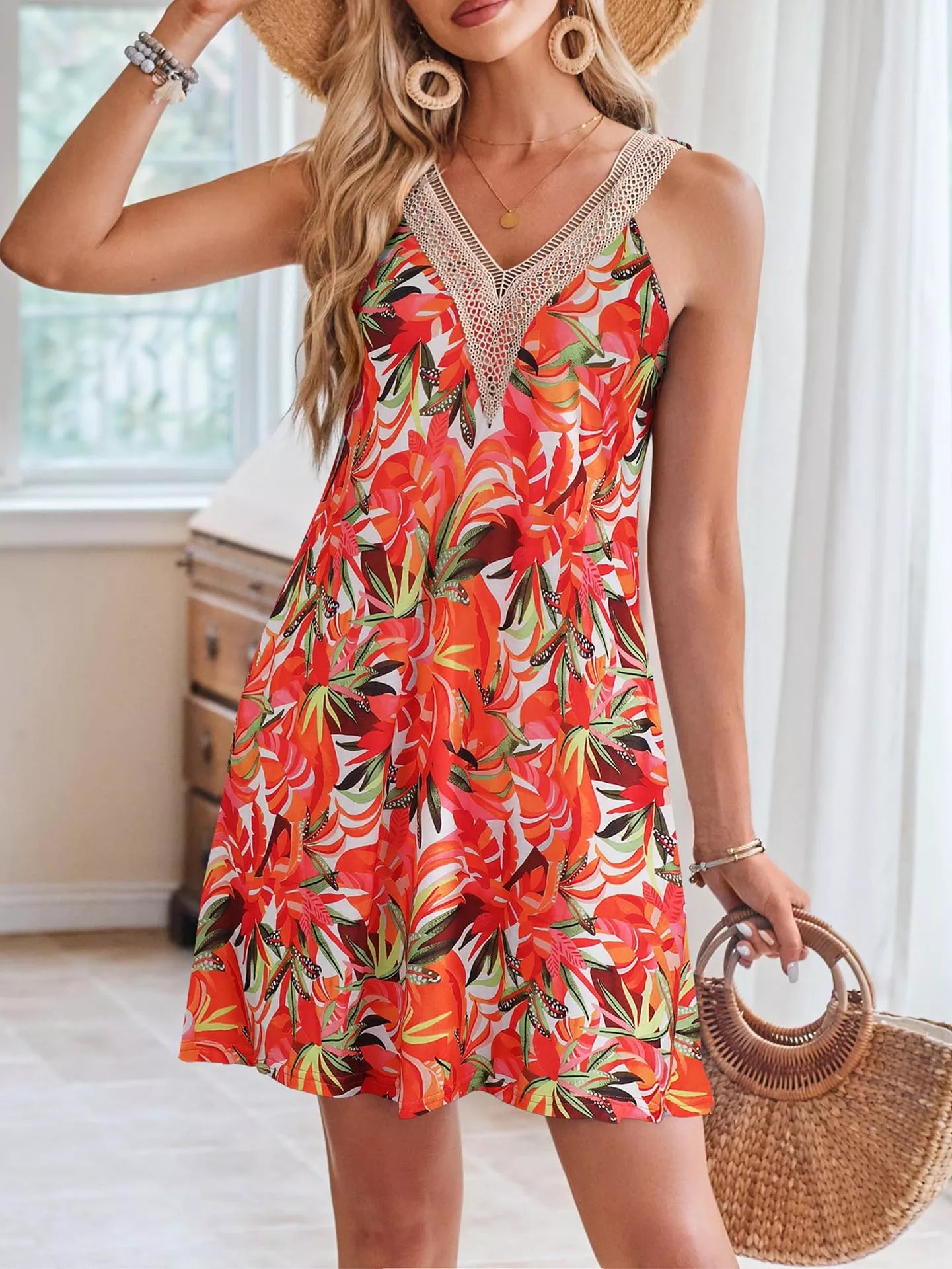 Woman wearing a colorful floral dress with a straw bag indoors.