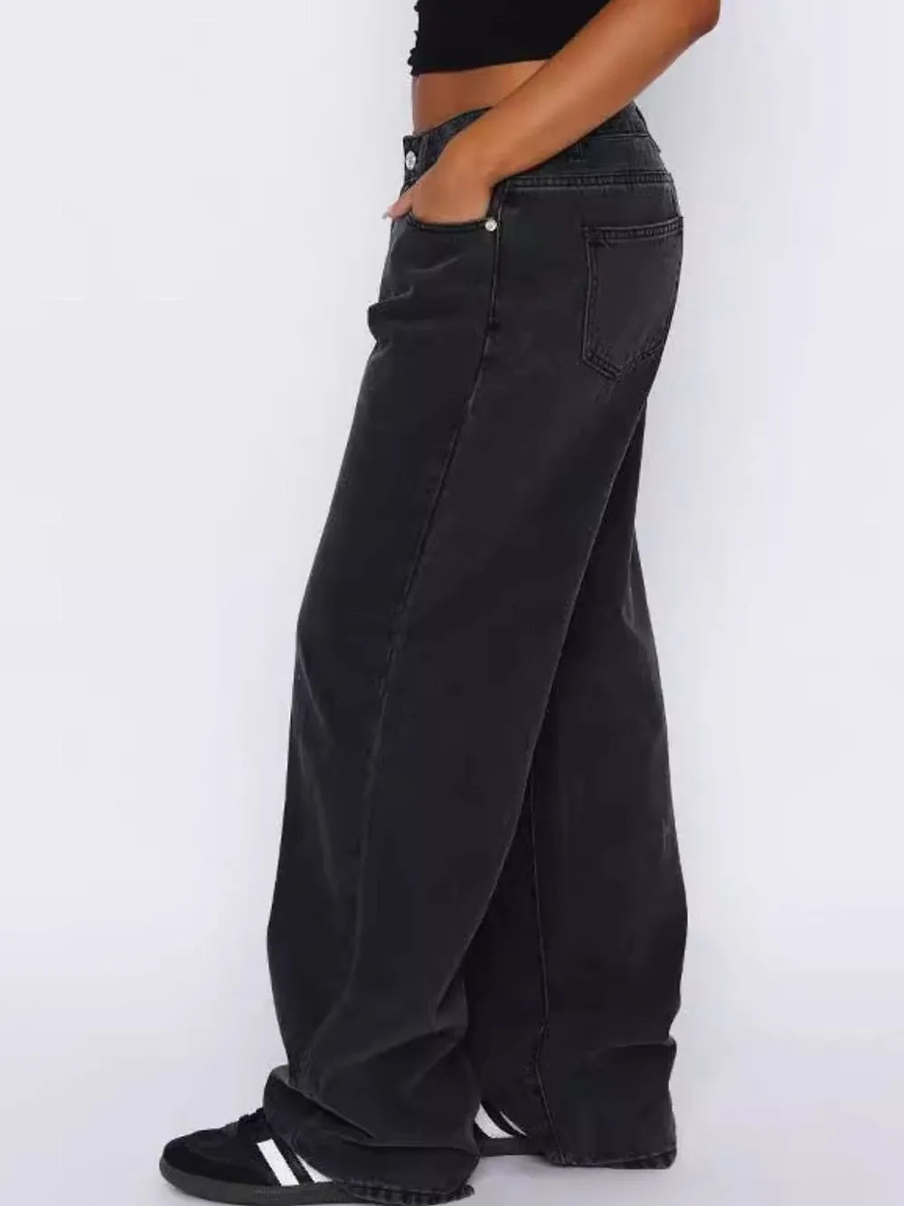 Person wearing black wide-leg jeans on a white background