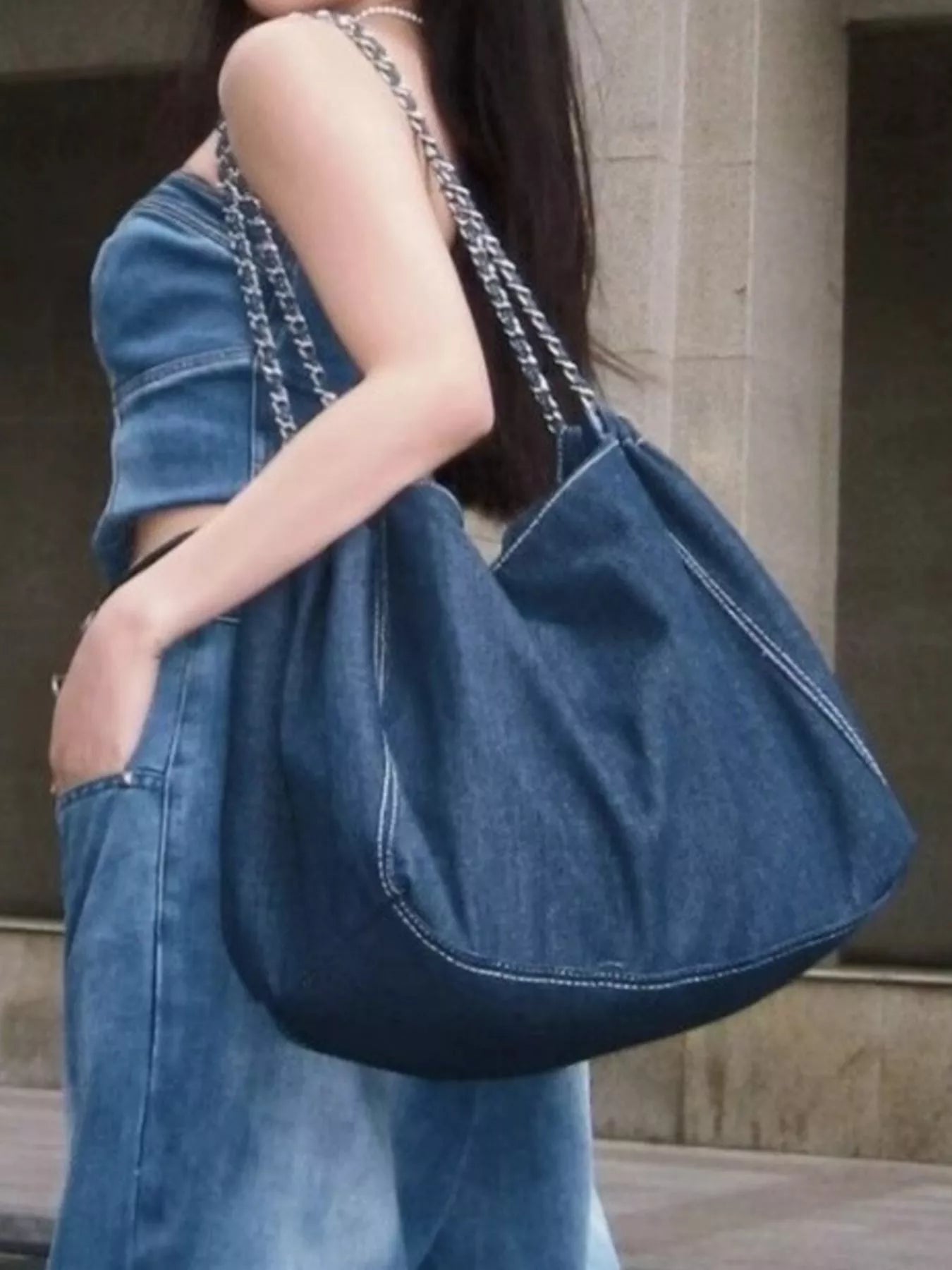 Person holding a denim handbag with a neutral background