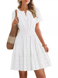 Woman wearing a white dress holding a brown and beige bag on a white background