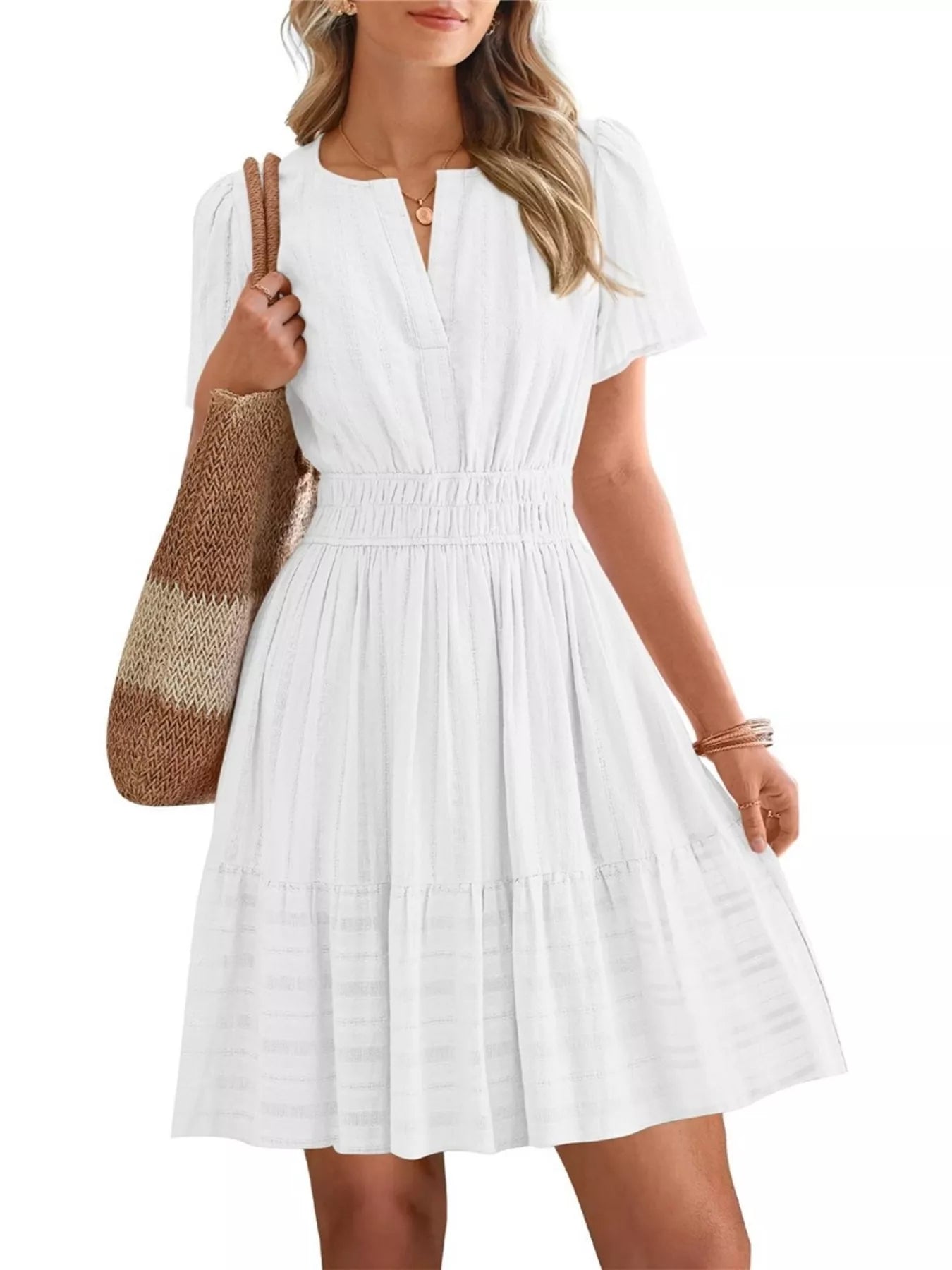Woman wearing a white dress holding a brown and beige bag on a white background