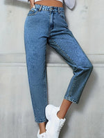 Person wearing blue jeans and white sneakers against a light gray background