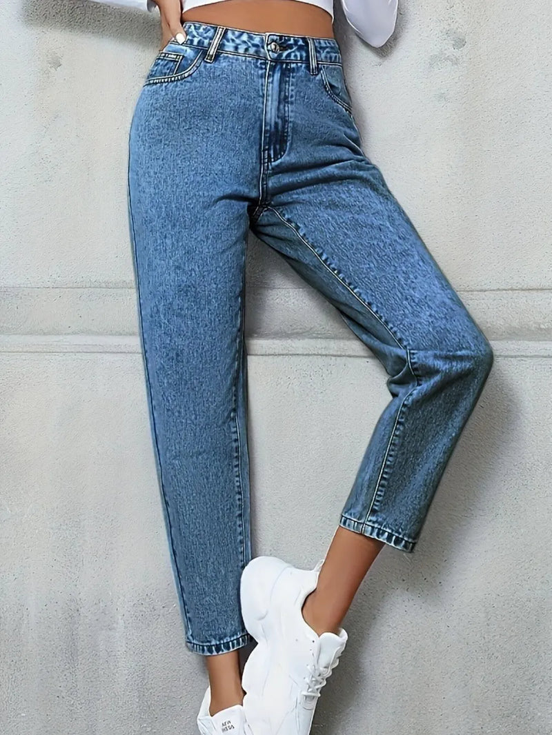 Person wearing blue jeans and white sneakers against a light gray background