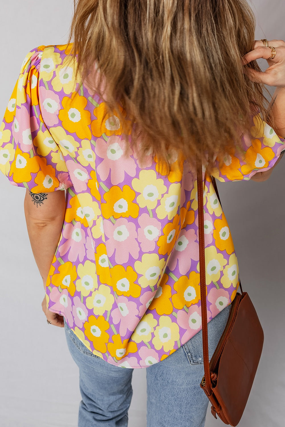 Person wearing a colorful floral blouse with a plain background