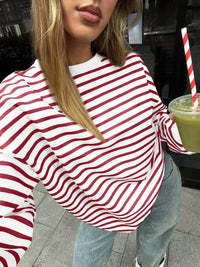 Person wearing a red and white striped shirt holding a green drink with a straw.