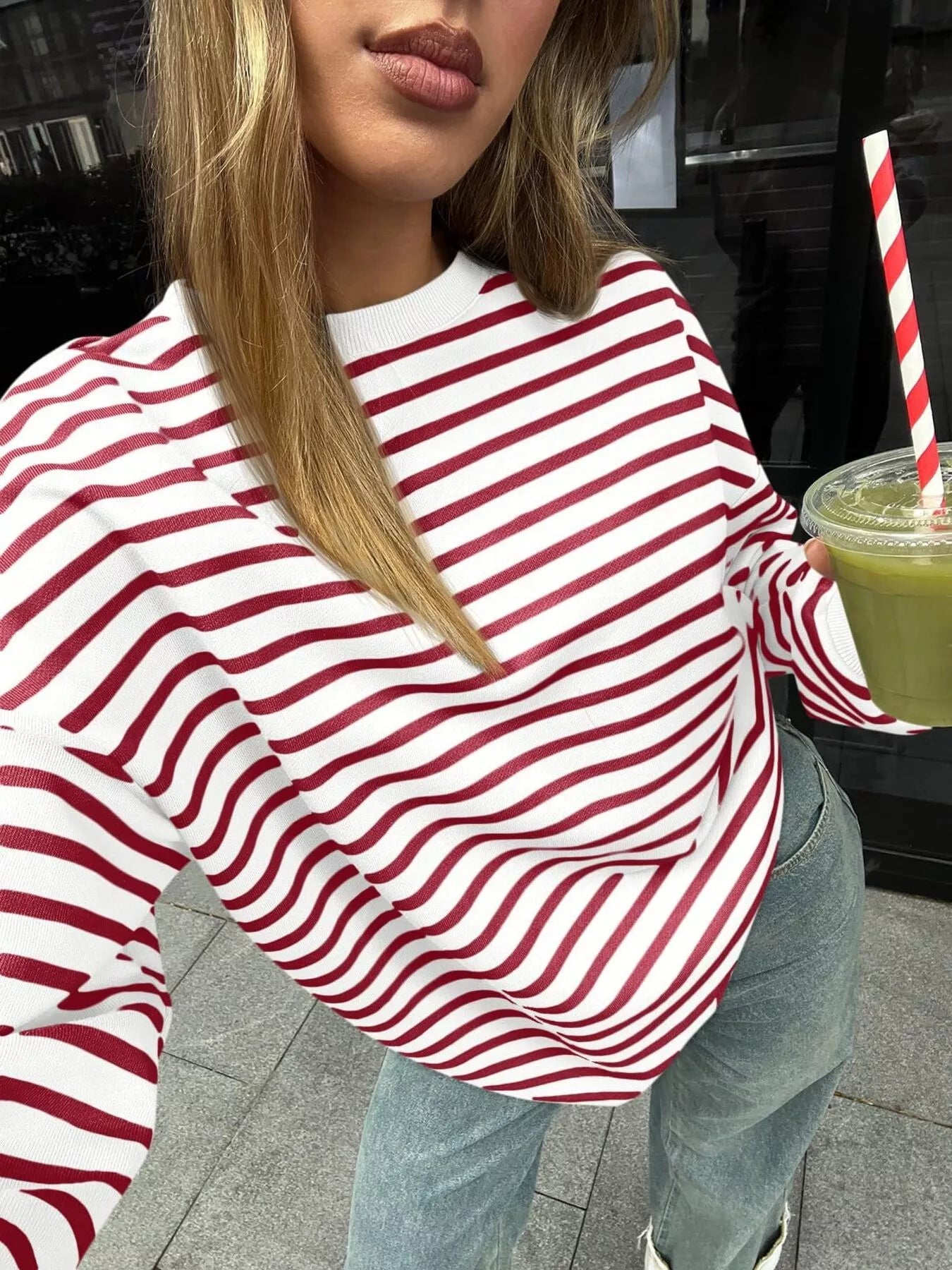 Person wearing a red and white striped shirt holding a green drink with a straw.