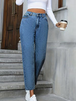 Person wearing blue jeans and a white top, holding a coffee cup, standing on steps.