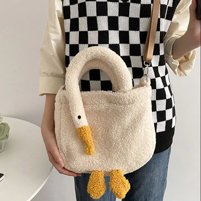 Person holding a fluffy white bag with yellow accents, resembling a swan, against a neutral background.