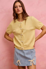 Woman wearing a yellow top and denim skirt against a pink background