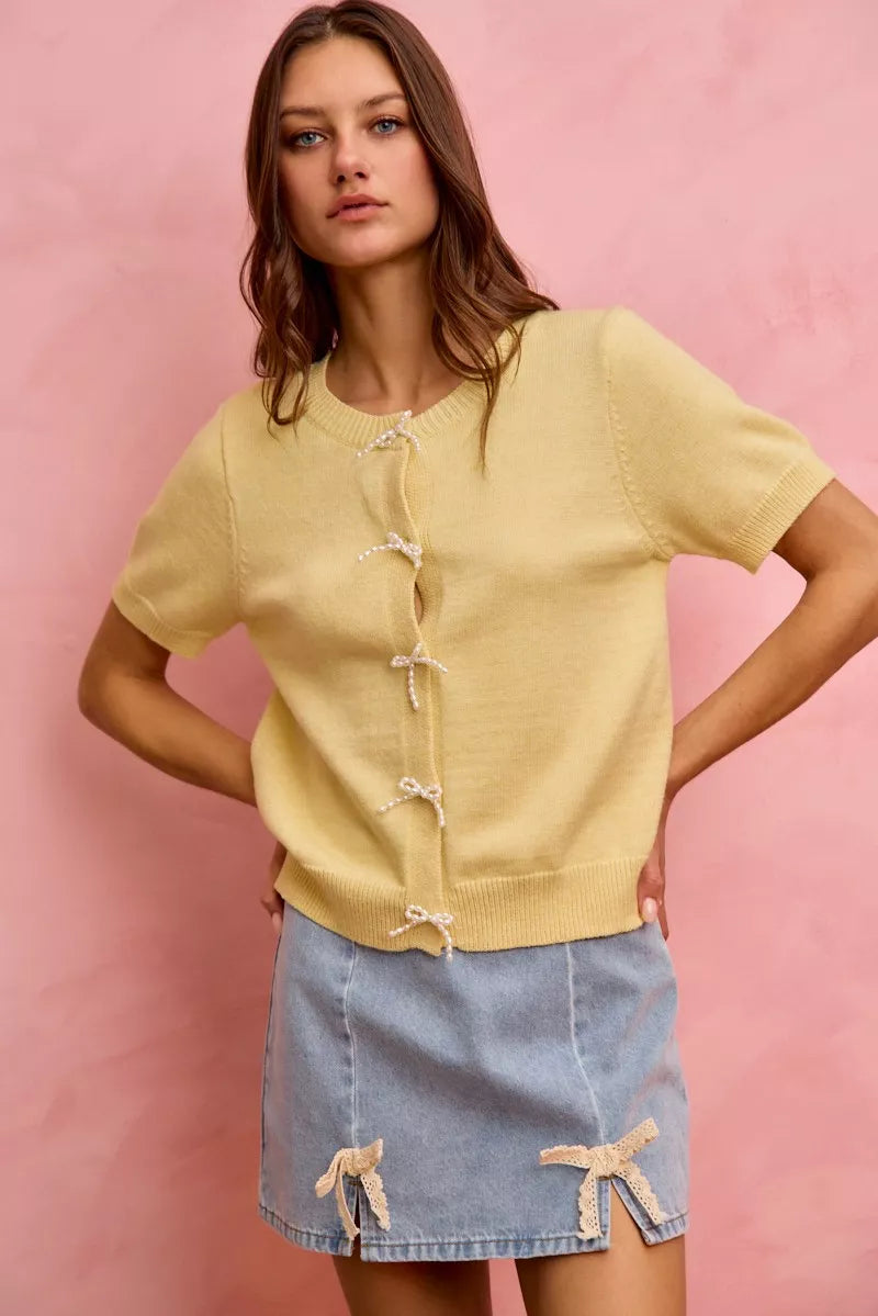 Woman wearing a yellow top and denim skirt against a pink background