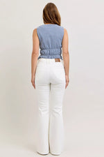 Woman wearing a blue checkered top and white pants on a plain background