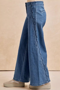 Blue jeans worn by a person on a beige background