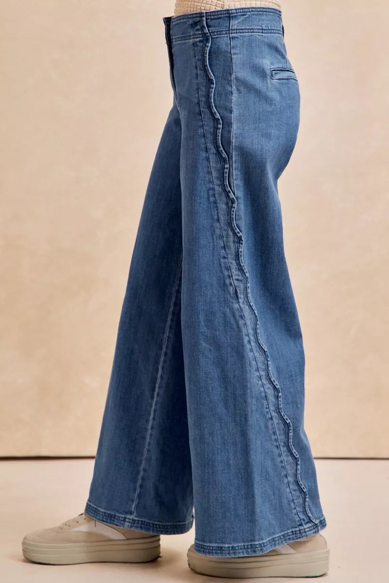 Blue jeans worn by a person on a beige background