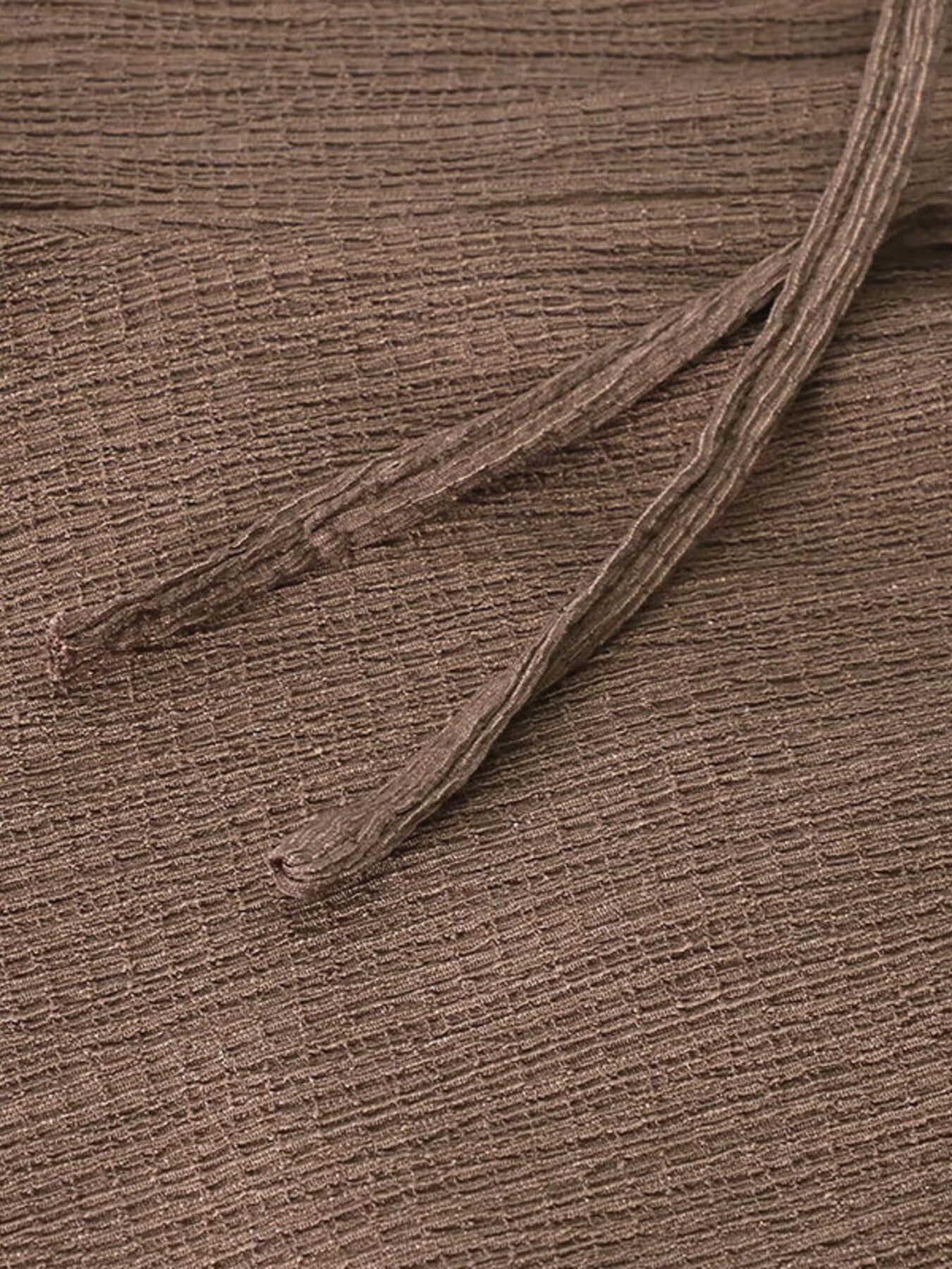Close-up of a brown fabric texture with a single thread