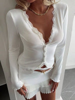 White lace dress with long sleeves and a gold belt on a plain background