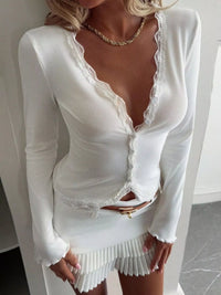 White lace dress with long sleeves and a gold belt on a plain background