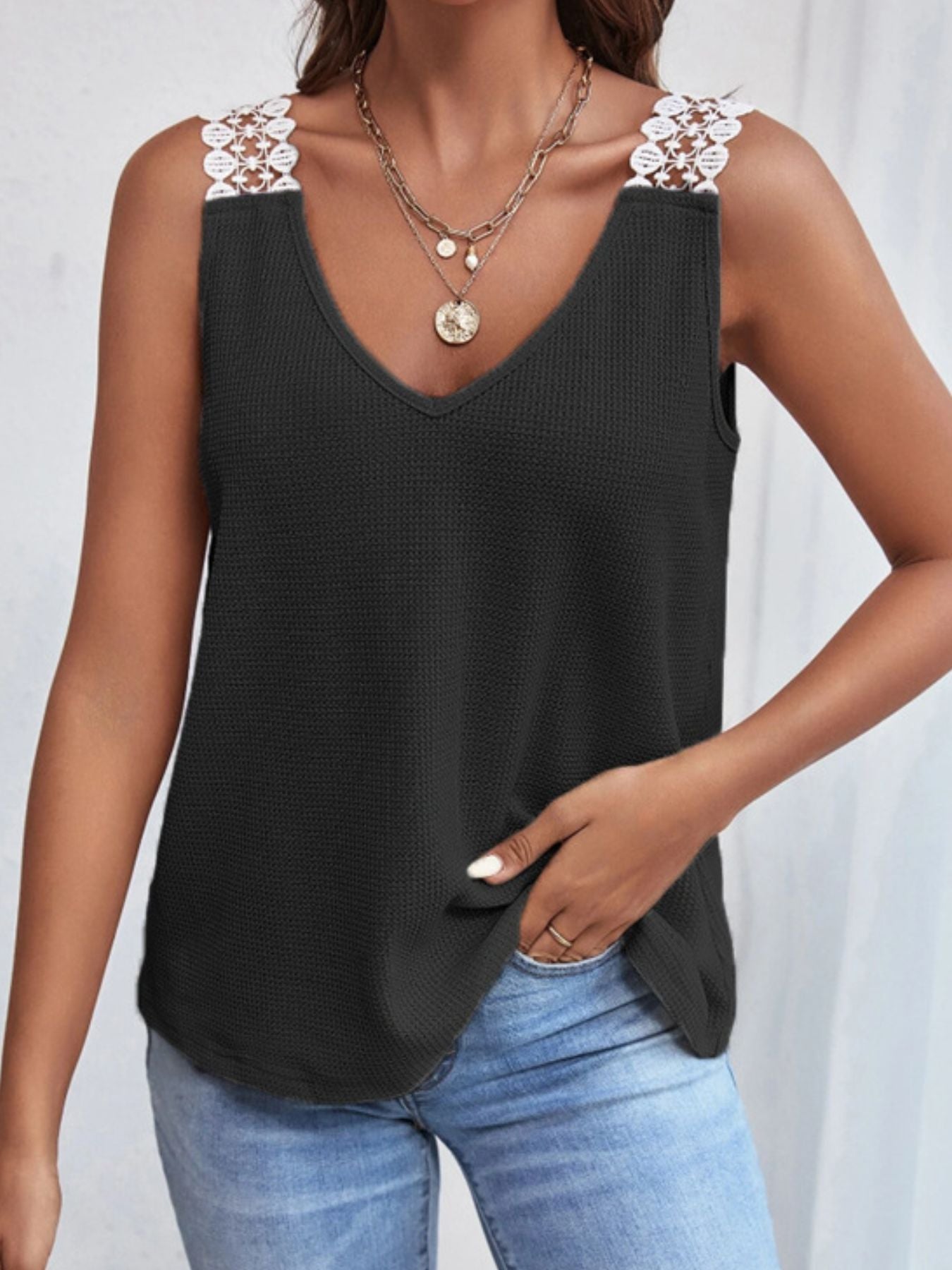 Black sleeveless top with floral straps worn by a person on a white background
