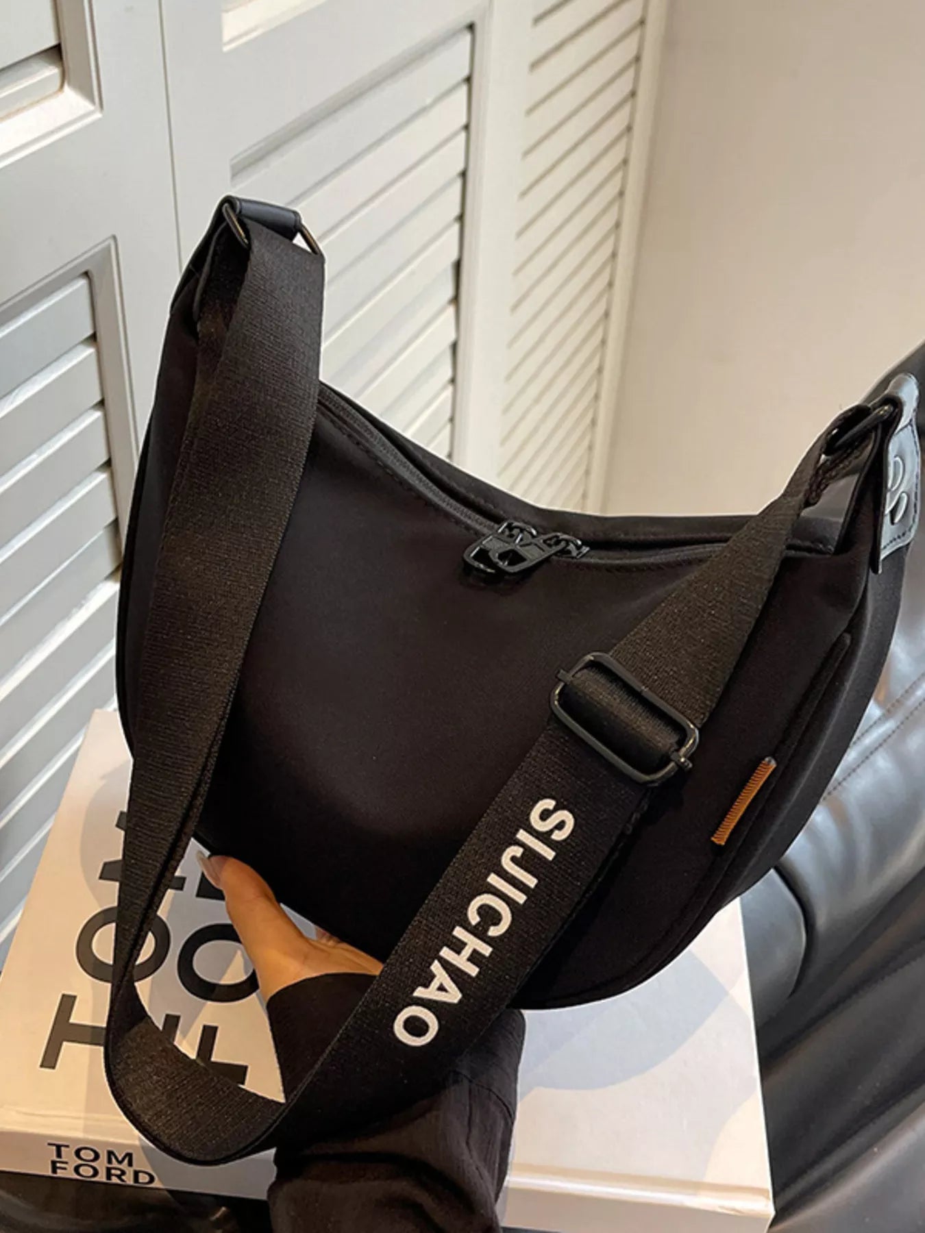 Black shoulder bag with 'SICHUA' branding on a surface with a blurred background