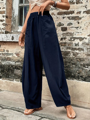 Person wearing navy wide-leg pants standing against a brick wall.