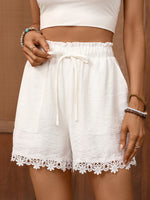 White lace-trimmed shorts worn by a person on a brown background