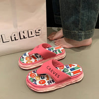 Pink children's sandals with colorful letter pattern on a neutral background